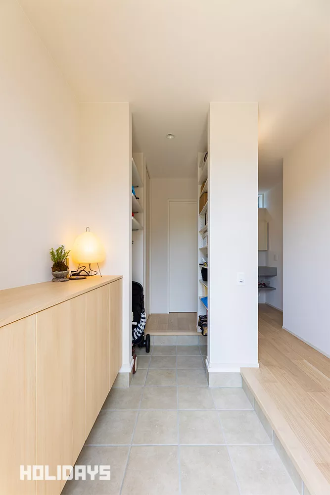 玄関収納はフロートタイプにすることで圧迫感のないスタイリッシュな印象に仕上げた。優しい色合いの木目柄を選択した事で、外観との統一感も生まれている。また、シューズインクロークも併設する事で、ベビーカーやアウトドア用品、子どもの外遊びグッズなど、玄関周りのものをまとめて収納することができる。