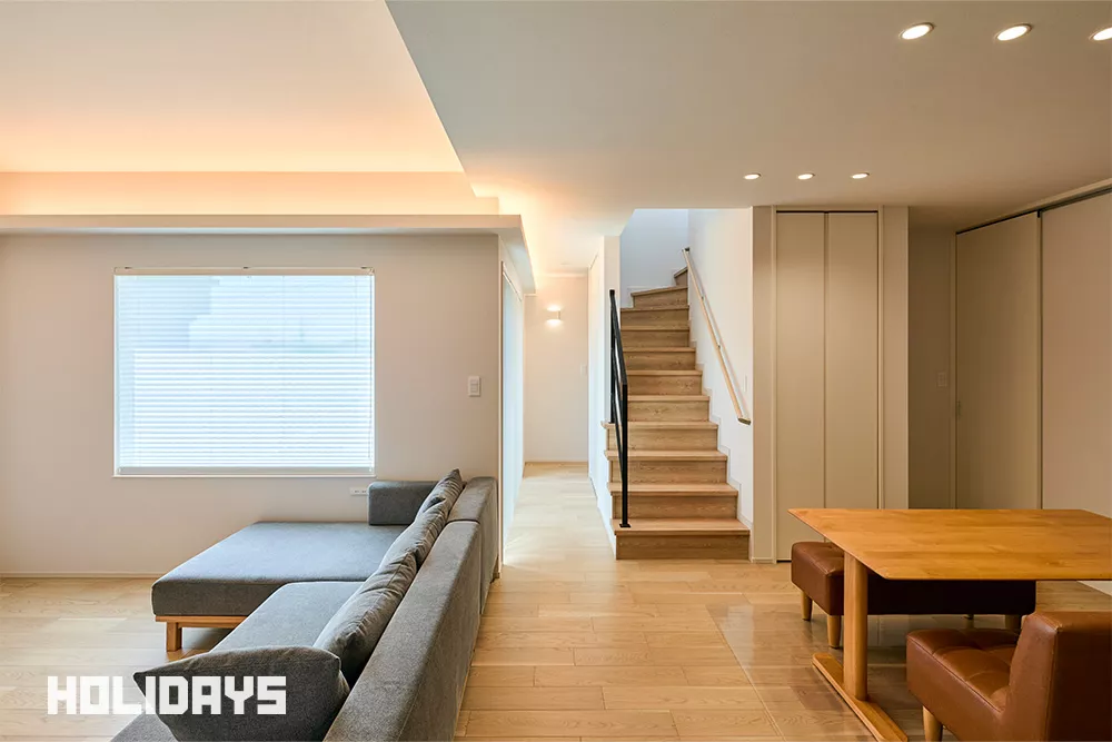 階段にはアクセントになるアイアン調の階段手摺を設置。リビングの間接照明は廊下部分にまで繋げ、どこからみても美しいホール空間となった。ブラインドカーテンは枠内付けの器具を選定し、色味もクロスに合わせることでノイズレスな空間を引き立てている。